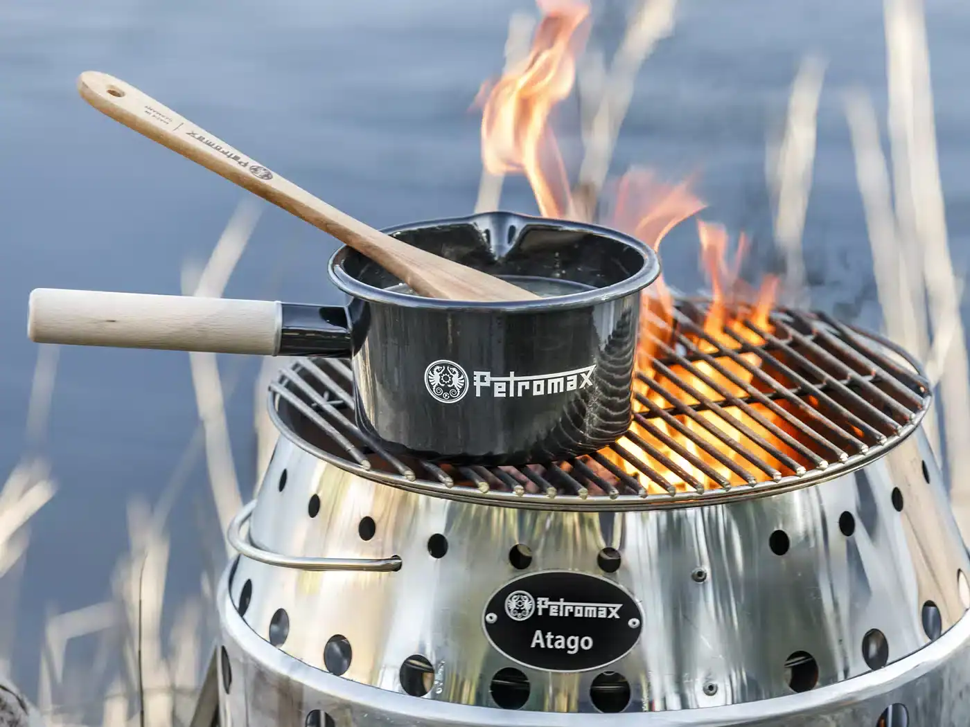 Petromax emaille pan op camping grill met vlammen.